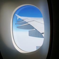 Cropped image of airplane flying over blue sky