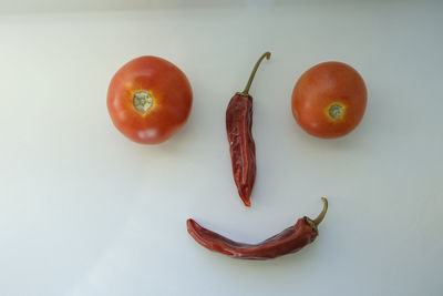 A red organic tomatoes and dried hot red pepper on the windowsill in the form of a smiley and emoji