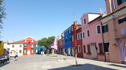 People walking on street amidst buildings against sky