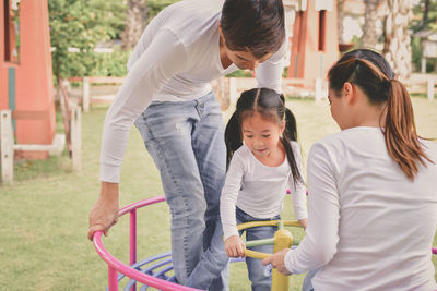 Parents with daughter in play equipment at park