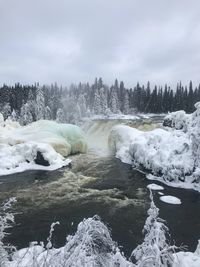 Scenic view of river by snow against sky during winter 
