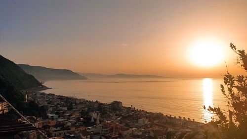 Scenic view of sea by buildings against sky during sunset