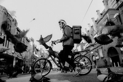 People riding bicycles on street against clear sky