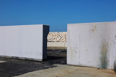 White wall by building against clear blue sky