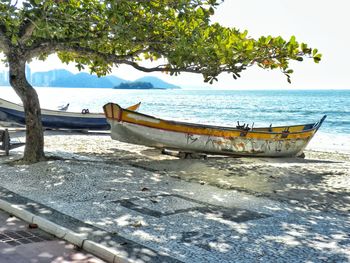 Boat moored on beach against sky