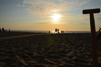 People on beach against sky during sunset