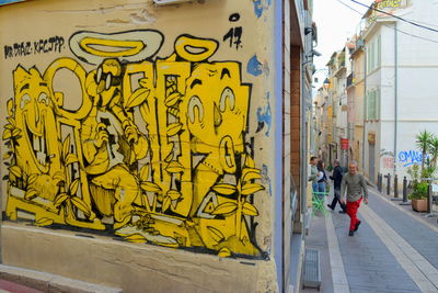 Rear view of man walking on graffiti wall