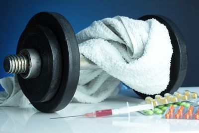 Close-up of pills and syringe by dumbbells on table