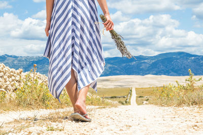 Low section of woman standing on land against sky