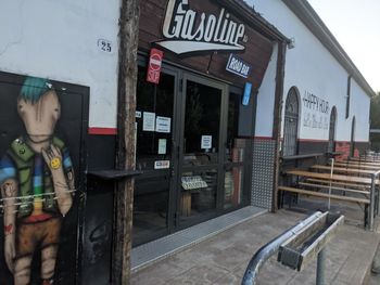 Reflection of boy on bus stop sign against store