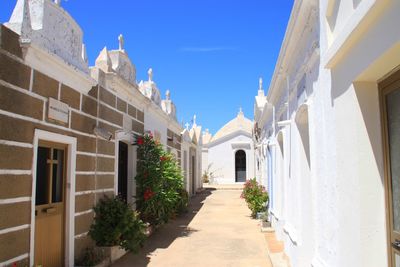Alley amidst buildings against blue sky
