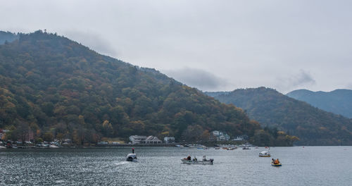 People on boat in lake against mountains