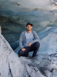 Portrait of man sitting on snowcapped mountain