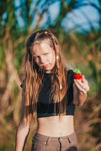 Portrait of young woman with eyes closed standing against plants
