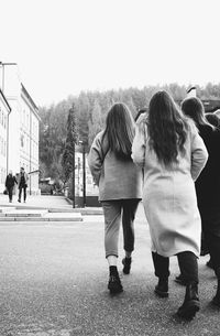 Rear view of women walking on road against sky