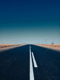 Empty road against clear blue sky