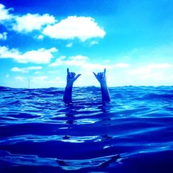 Woman swimming in sea against blue sky