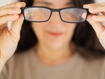 Close-up portrait of woman holding eyeglasses
