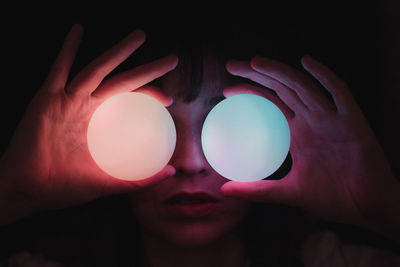 Close-up of hand holding crystal ball against black background