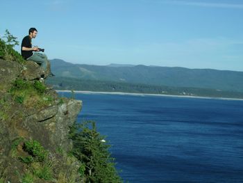 Woman standing on rock by sea against clear sky