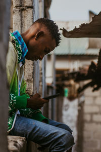 Side view of young man holding smart phone