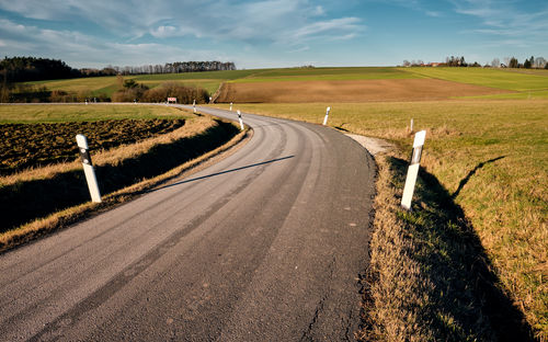 Road amidst agricultural field against sky