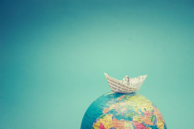 Close up of paper boat on globe over blue background