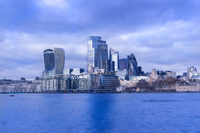 Modern buildings in city against cloudy sky