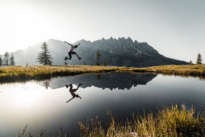 Human flying over lake against sky