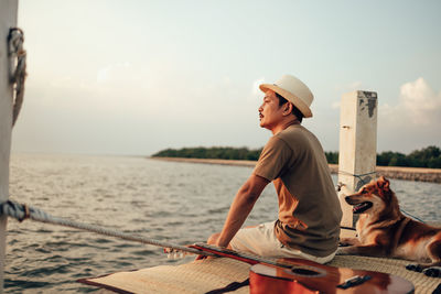Man sitting in sea against sky