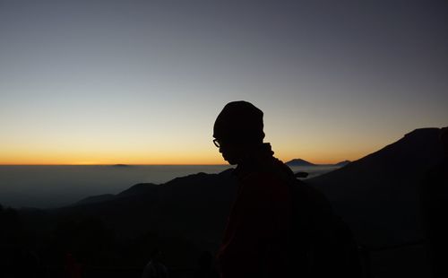 Silhouette man standing on mountain against sky during sunset