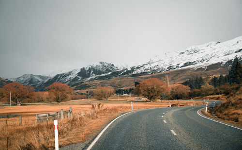 Road leading towards snowcapped mountains against sky