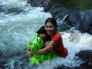 Portrait of happy mother with daughter in river