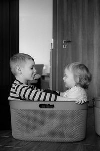 Cute sibling sitting in basket at home