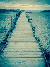 Wooden pier at sea shore against sky