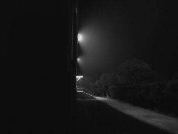 Empty road along illuminated lights at night