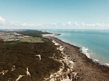 Scenic drone view of beach and coast against sky