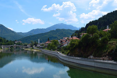 Scenic view of river by buildings against sky