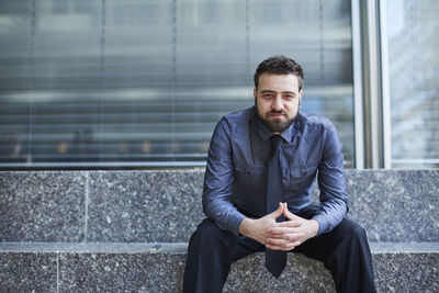 Portrait of young man using mobile phone in city