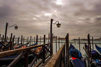 View of wooden posts in sea against cloudy sky