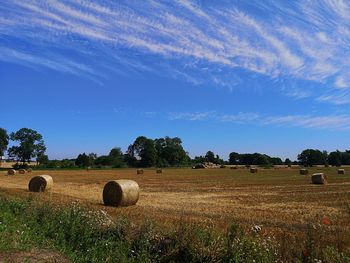 Hay bales on field against sky