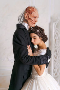 Beautiful girl in white dress and scary disfigured man in black stand