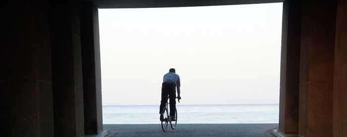 Rear view of man looking at sea against sky