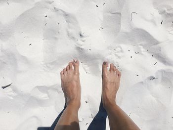 Low section of woman standing on sand