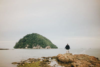 Rear view of man overlooking calm sea