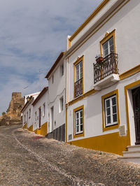 Residential buildings by street against sky