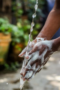 Close-up of hand holding wet glass during rainy season