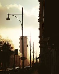 Street lights in city against sky during sunset