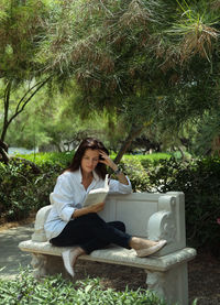 Young woman sitting outdoors with book