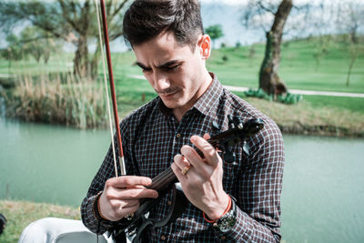 Young man looking at camera while standing by lake